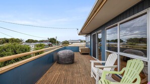 Un balcon offrant une vue sur les environs, un plancher en bois et un espace salon extérieur.