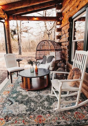 A cozy outdoor seating area with a round table, white chairs, and a cushioned bench.