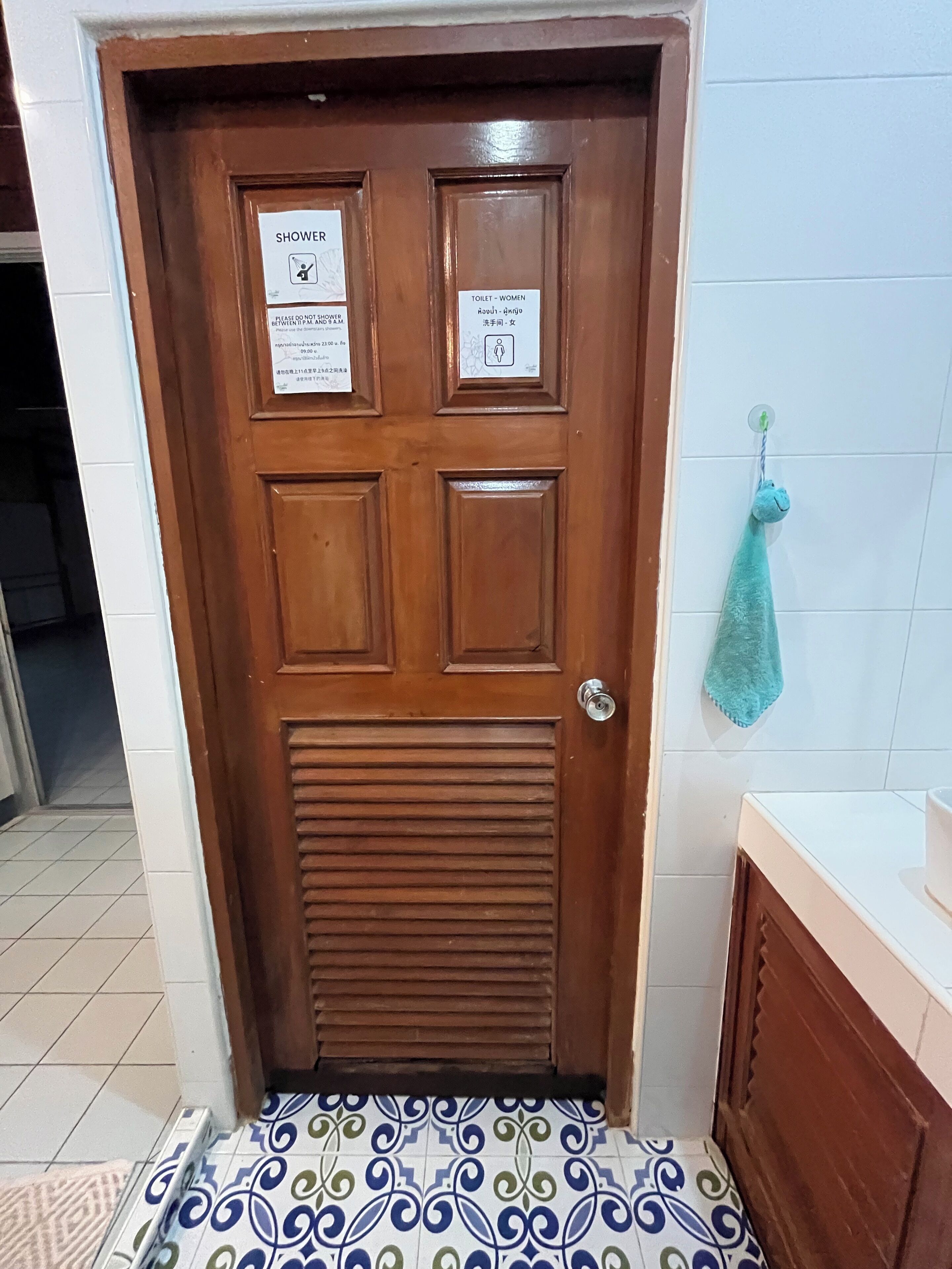A wooden door with signs indicating a shower and a women's toilet.