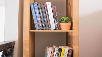 A wooden bookshelf with two shelves, each holding books and small potted plants.