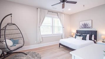 A bedroom with a bed, a hanging chair, a ceiling fan, and a window with curtains.