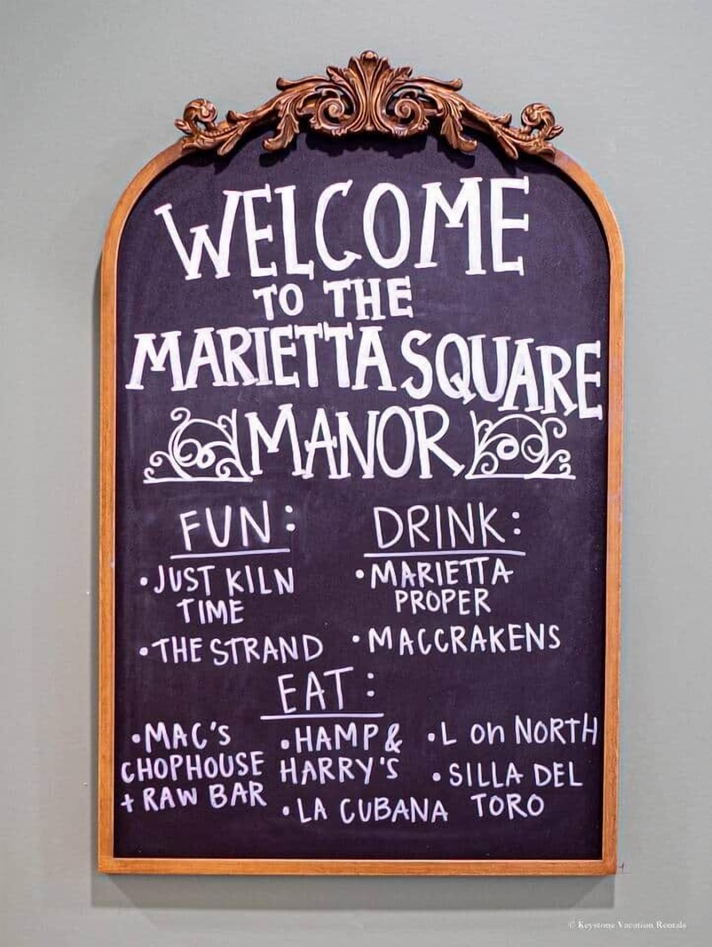 Señal de bienvenida a Marietta Square Manor, que muestra actividades divertidas, bebidas y opciones gastronómicas.
