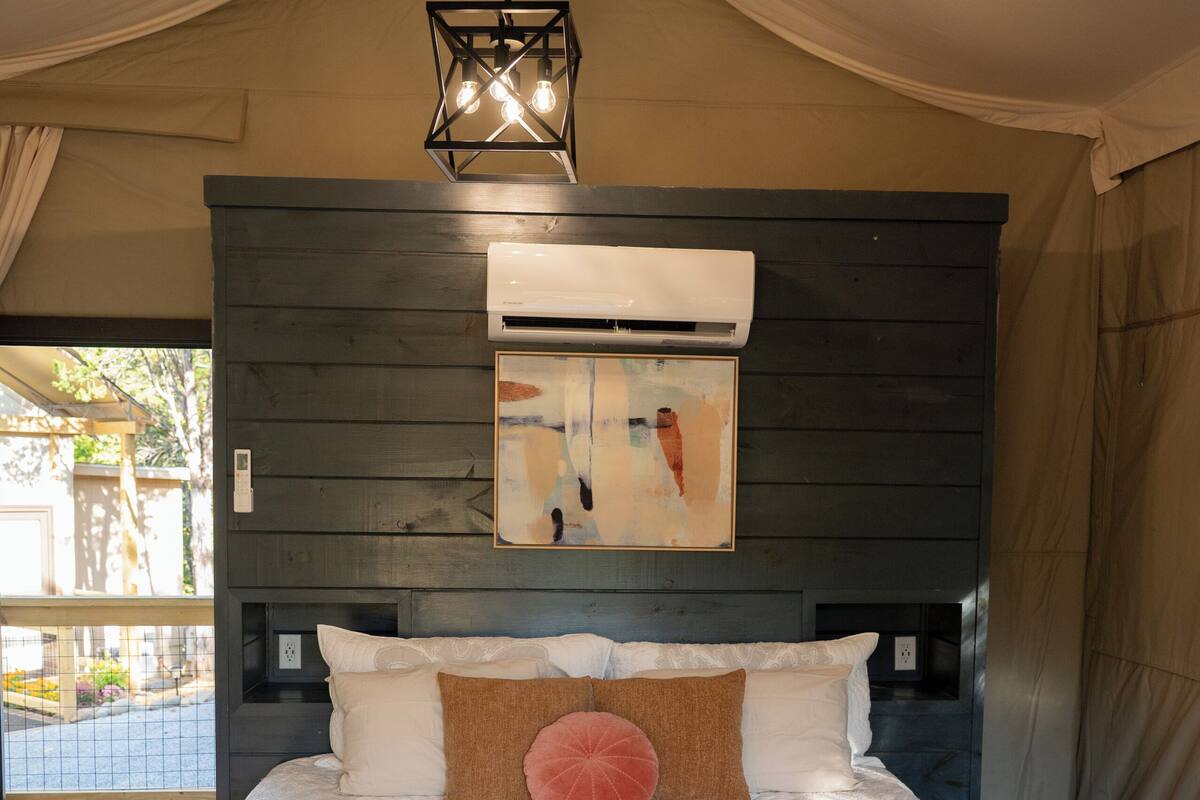 A bedroom with a large bed, a hanging light fixture, and a painting on the wall.