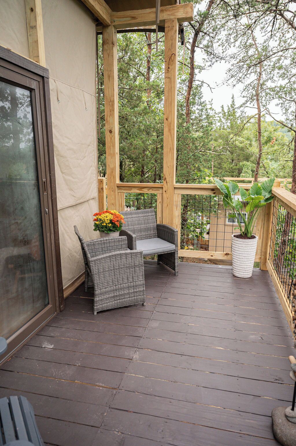 A wooden deck with wicker furniture and a potted plant.
