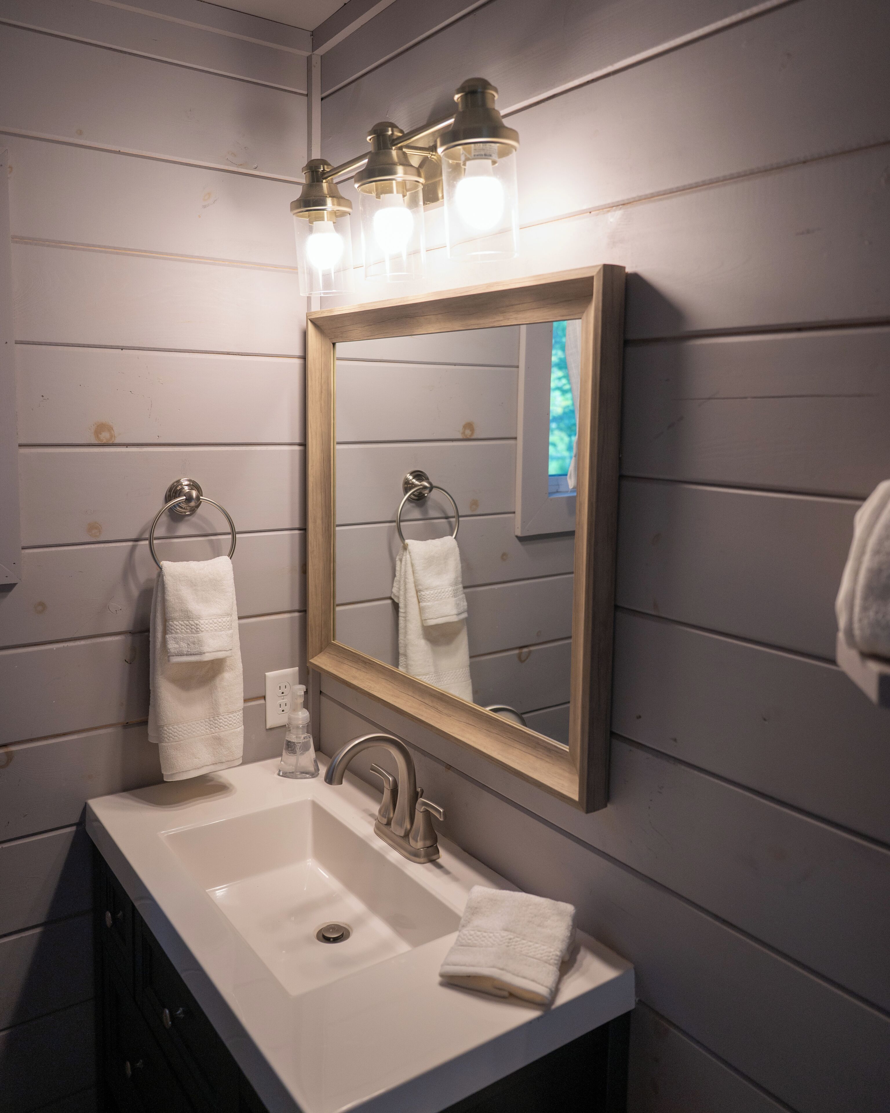 A bathroom with a white sink, a mirror, and two towels hanging on towel rings.