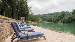 A lakeside setting with lounge chairs and a lifeguard tower. - WYLDSTAY Smoky Mountains (Sevierville)