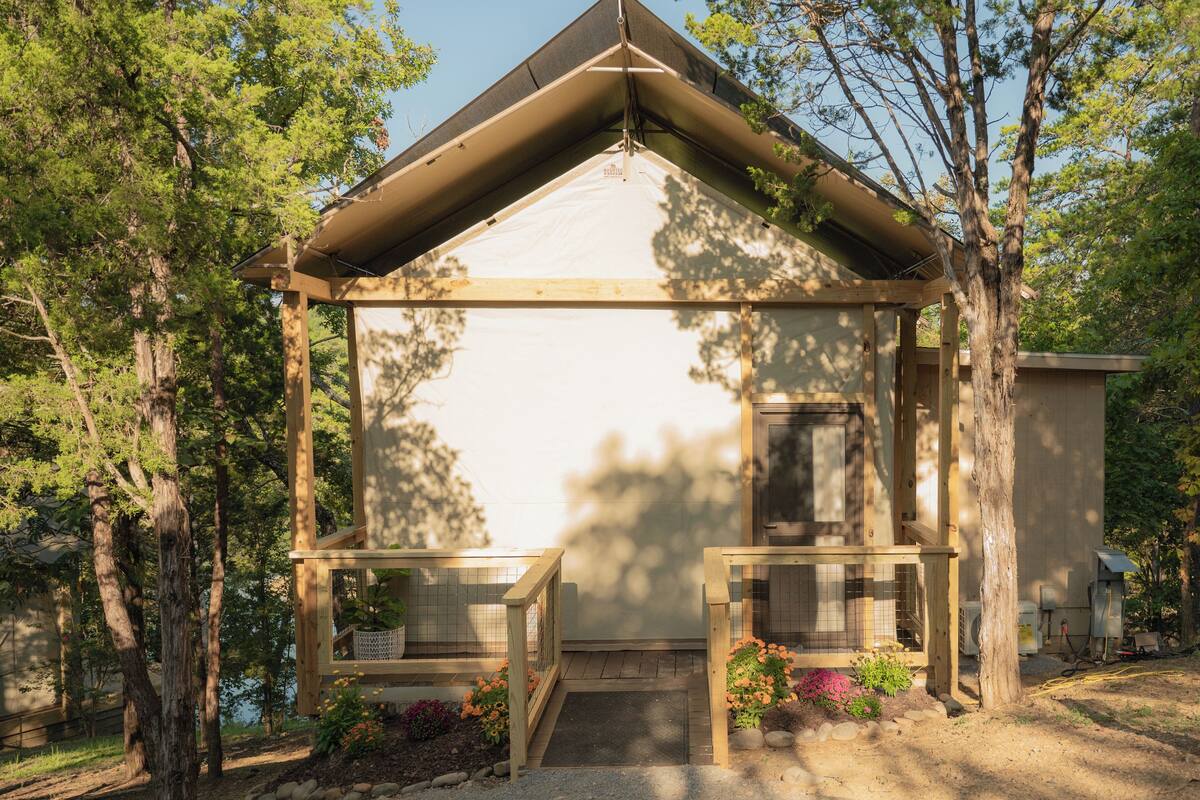 A small wooden structure with a pitched roof, a door, and a small porch area with steps.