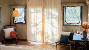 A tented room with a bed, a chair, a table with a vase, and a ceiling fan. - WYLDSTAY Smoky Mountains (Sevierville)