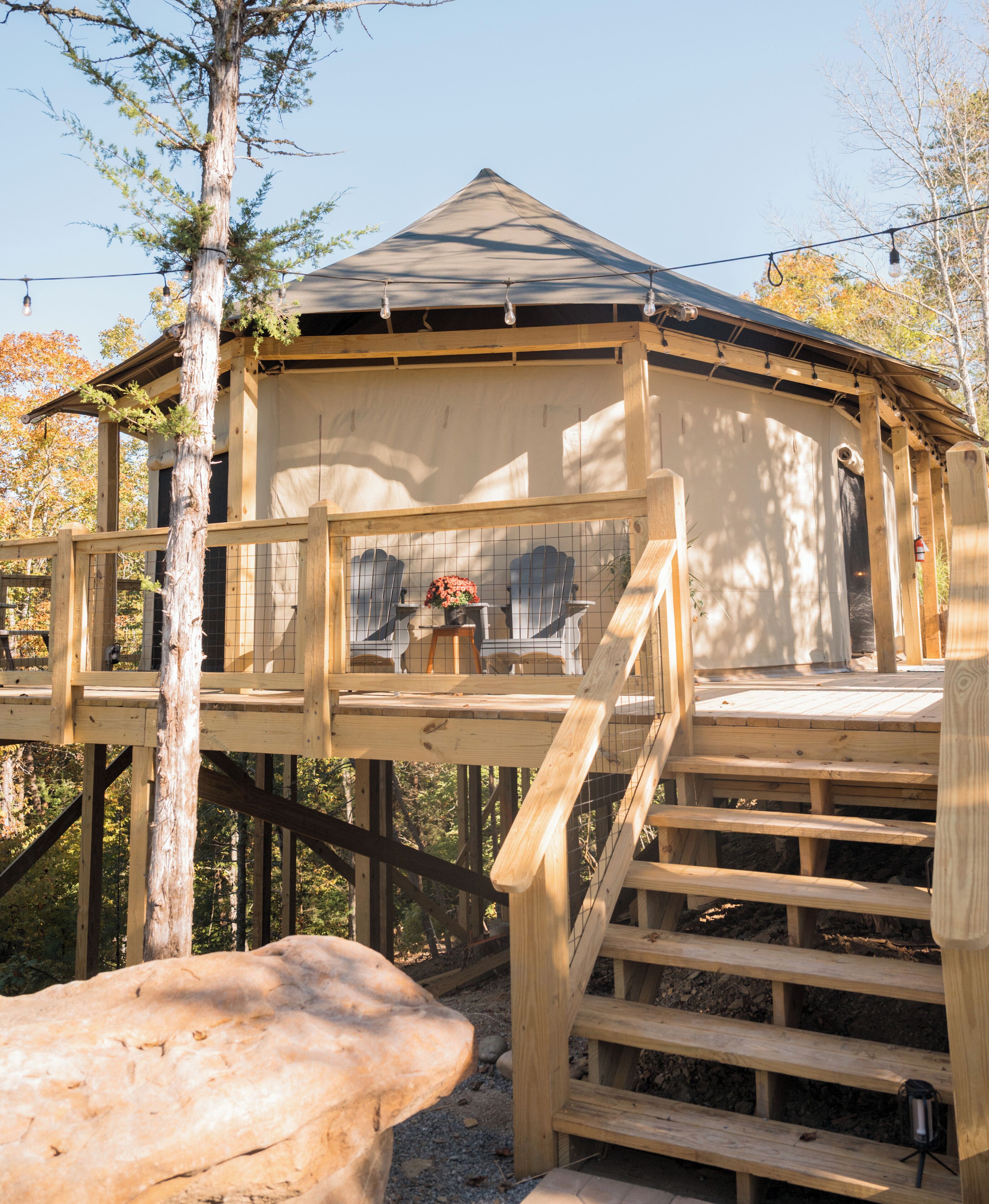 Ein hölzernes Gartenhaus mit geneigtem Dach, einer Holzterrasse und einem Geländer.