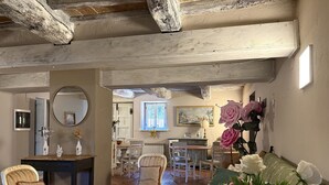 Ein geräumiges Wohnzimmer mit hoher Decke, einem Essbereich mit Tisch und Stühlen sowie einer gemütlichen Sitzecke mit Sofa und einer Zimmerpflanze.