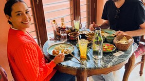 A dining table with various dishes, a bottle, and glasses. - Baari the house fusion (Jaipur)