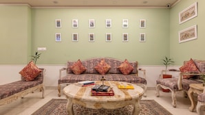 A living room with a sofa, two armchairs, a coffee table, and a patterned rug. - Baari the house fusion (Jaipur)