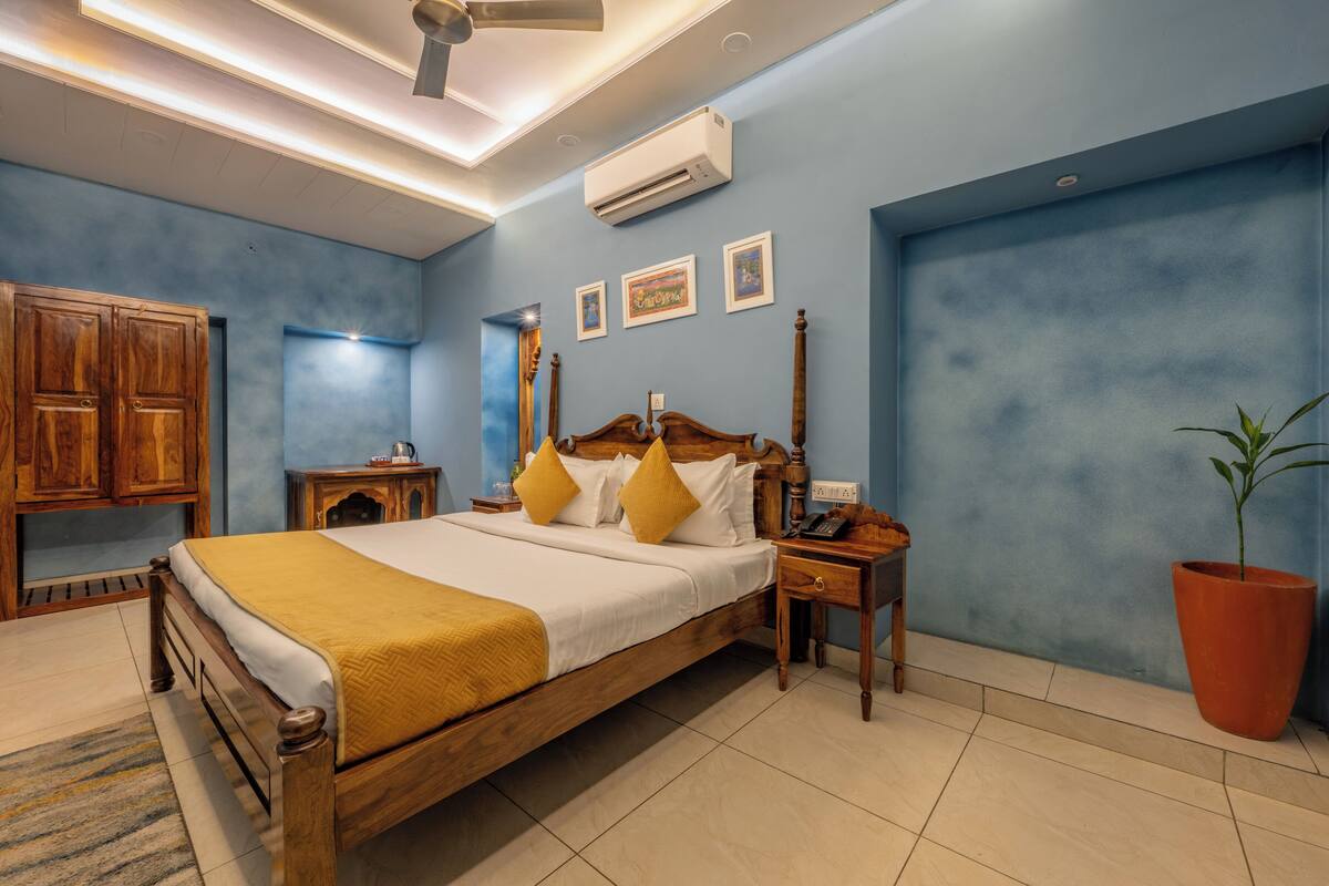 A bedroom with a wooden bed, a nightstand, a potted plant, and a ceiling fan.