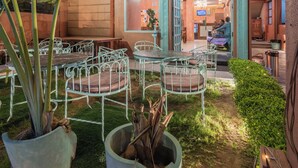 An outdoor seating area with metal chairs and tables, surrounded by potted plants. - Baari the house fusion (Jaipur)