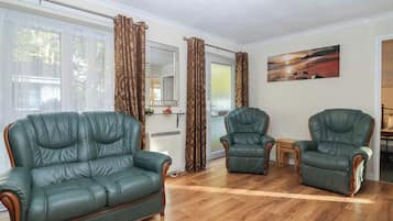 A living room with two green leather sofas, a wooden coffee table, and a painting on the wall.