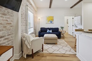 Un salon avec un canapé, un pouf et un tableau accroché au mur.