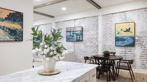 A modern kitchen with a marble countertop, a potted plant, and a dining area with a round table and chairs. - Adam Trest Suite, Laurel, Coffee Bar, Walkable (Laurel)