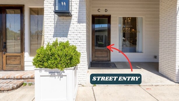 A street entry to a building with a white brick facade, a wooden door, and a sign indicating 'C D'. - Adam Trest Suite, Laurel, Coffee Bar, Walkable (Laurel)