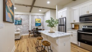 A modern kitchen with white cabinets, stainless steel appliances, and a marble island. - Adam Trest Suite, Laurel, Coffee Bar, Walkable (Laurel)