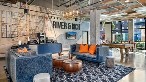 A modern lounge area with a large map on the wall, a bar, seating with orange cushions, and a pool table. - The Urban Loft Free Parking 9 Minutes To OSU (Columbus)