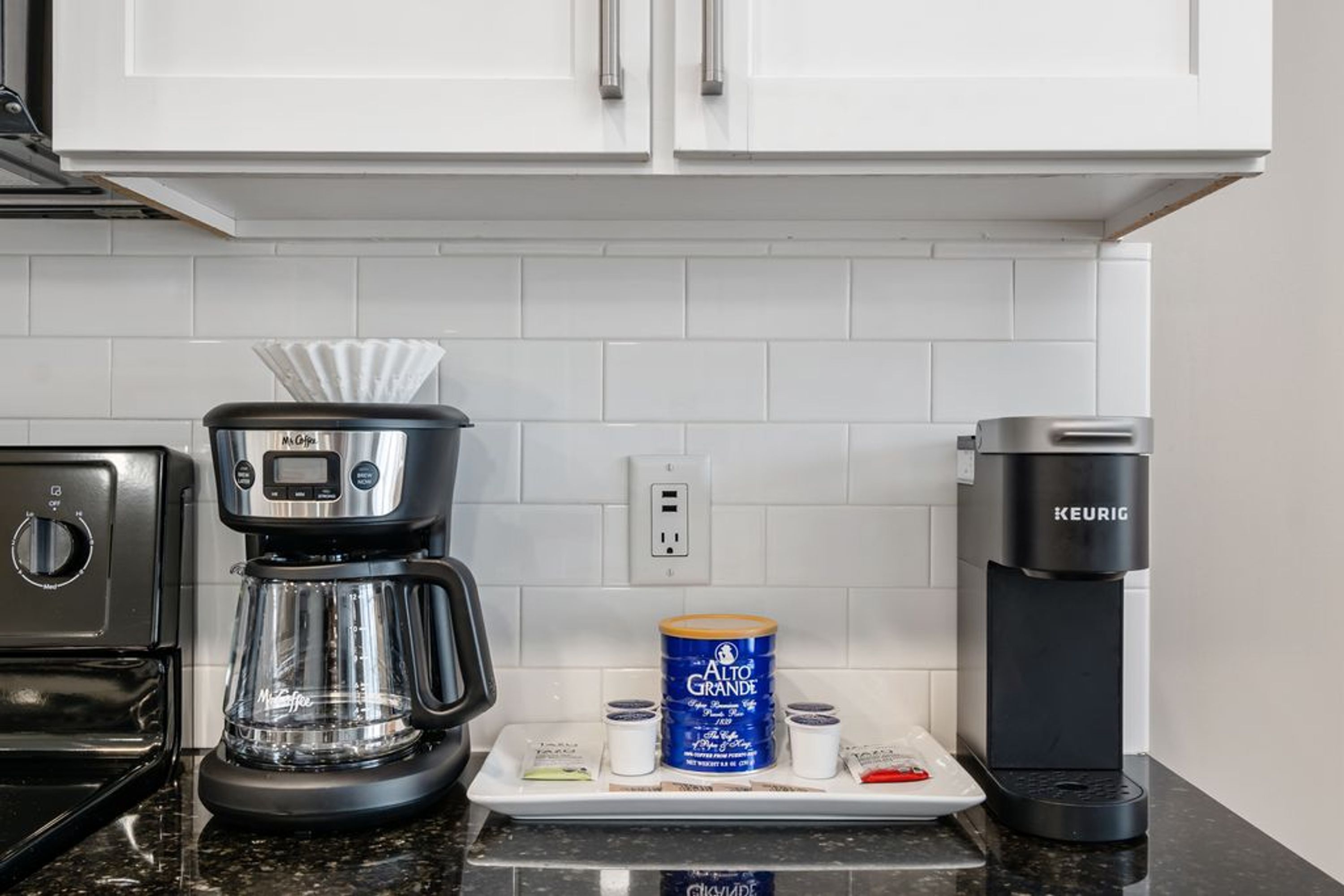 A kitchen with a coffee maker, a kettle, and a coffee pod dispenser.