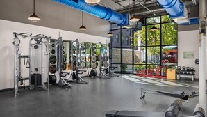 A gym with weightlifting equipment, benches, and a large window with a view of trees. - The Urban Loft Free Parking 9 Minutes To OSU (Columbus)