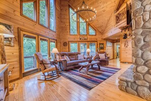 A spacious wooden interior with a large sofa, rocking chairs, and a stone fireplace. - NEW! Ultimate Trout Fishing on FIGHTINGTOWN CREEK, Hot Tub & fenced yard (Epworth)