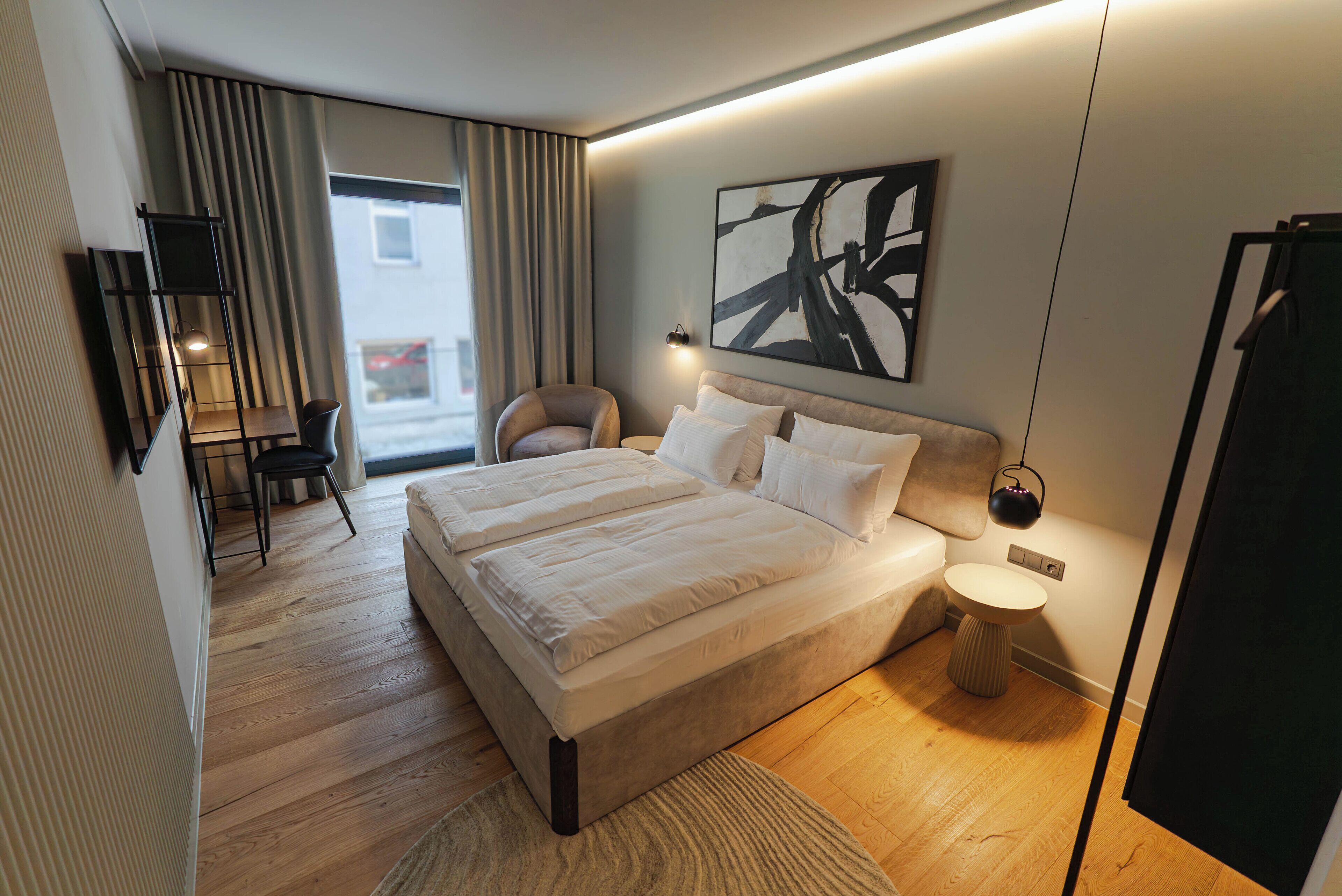 A modern hotel room with a large bed, a desk, and a chair.