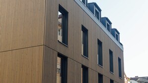A modern building with a wooden facade, multiple windows, and a flat roof. - Conlon House Lower East Side (Munich)