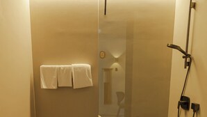 A modern bathroom with a glass shower enclosure, a toilet, and a wooden vanity. - Conlon House Lower East Side (Munich)