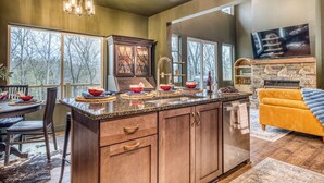 A modern kitchen with a large island, wooden cabinets, and a stone fireplace. - Charming Mountain Home- Gather, Relax, Explore (Ranger)