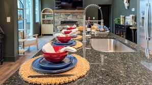 A kitchen with granite countertops, a stainless steel sink, and a stone fireplace. - Charming Mountain Home- Gather, Relax, Explore (Ranger)