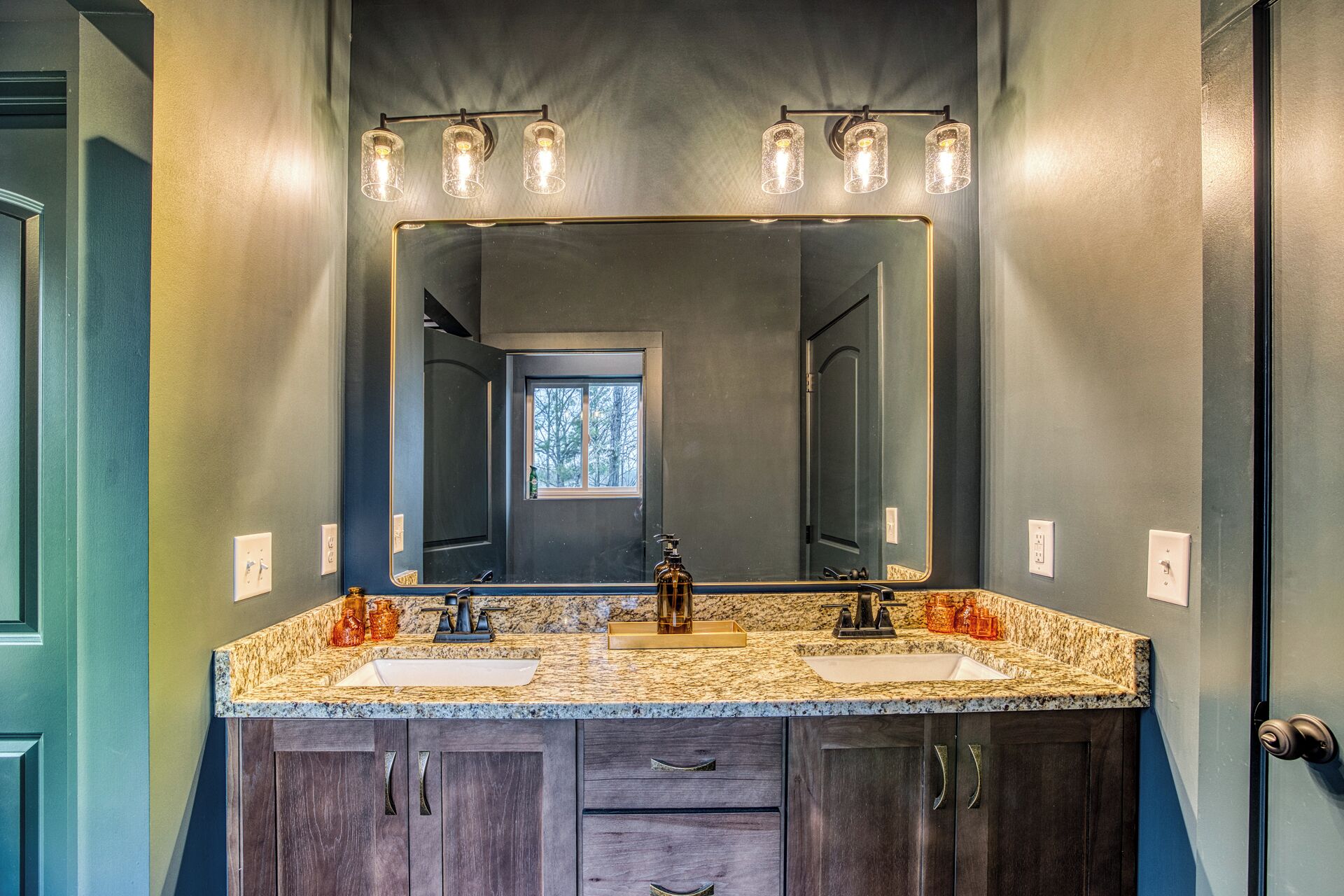 A bathroom with a large mirror, two sinks, and a vanity with drawers.
