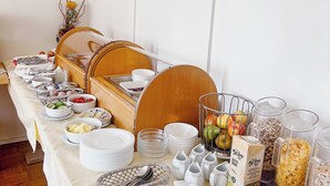 A breakfast buffet setup with various food items and utensils. - Hotel Albers (Recklinghausen)