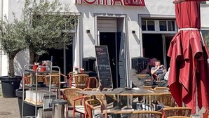 A building with a white facade, numbered 1766, featuring a sign for 'Nona Di Mia' and outdoor seating with wicker chairs and a red umbrella. - Hotel Albers (Recklinghausen)
