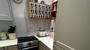 Una cucina compatta con un piano cottura, forno e tostapane in acciaio inossidabile. Sul muro è presente un orologio e sopra il bancone una spechiera.