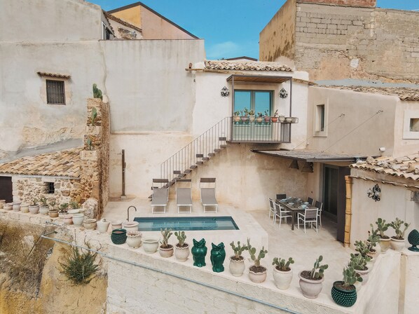 A courtyard with a pool, outdoor seating, and potted cacti.