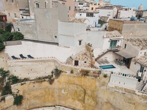 A courtyard with a swimming pool, lounge chairs, and a staircase leading to a rooftop area.