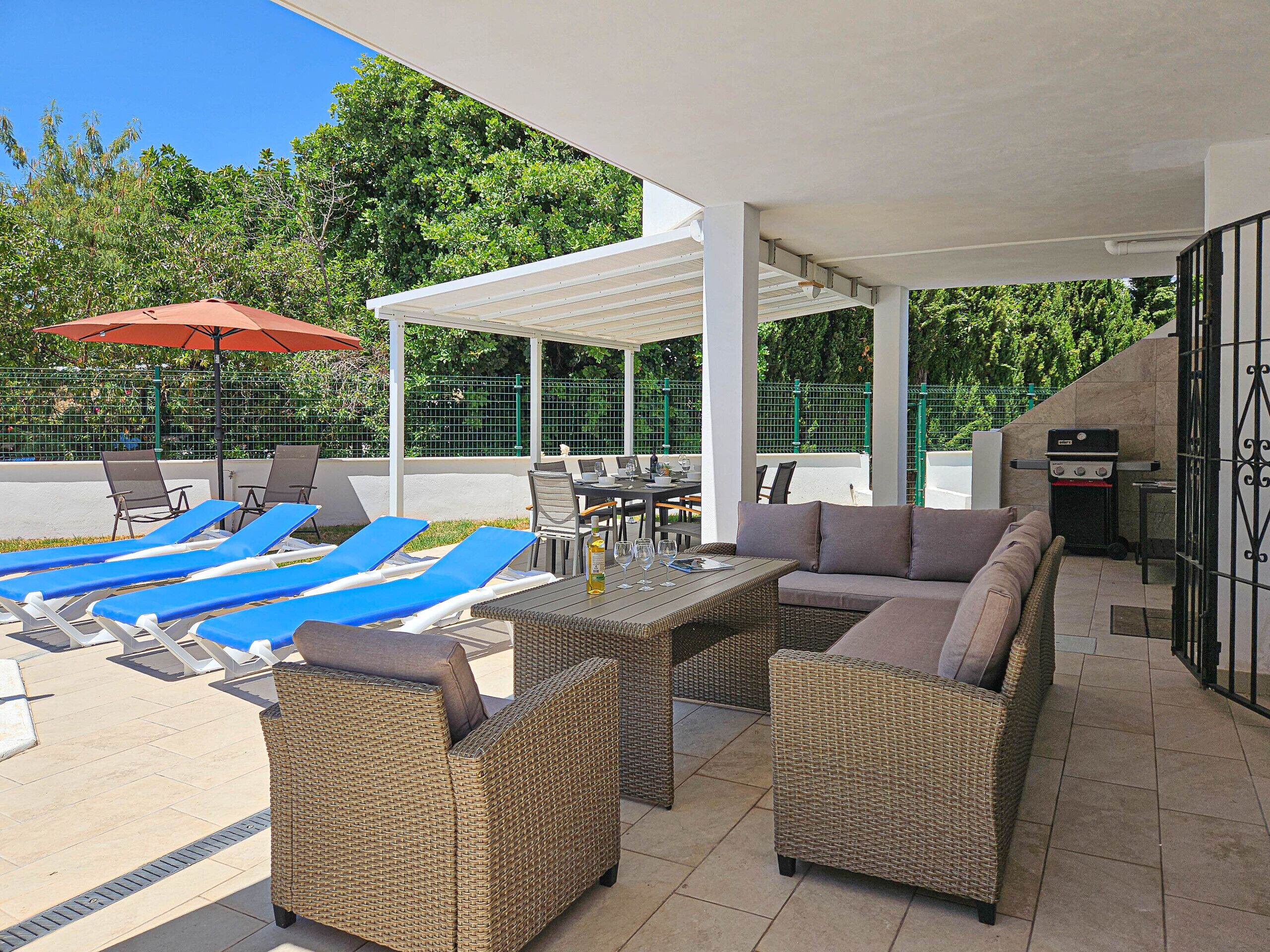 An outdoor patio area with lounge chairs, a dining table, and a grill.
