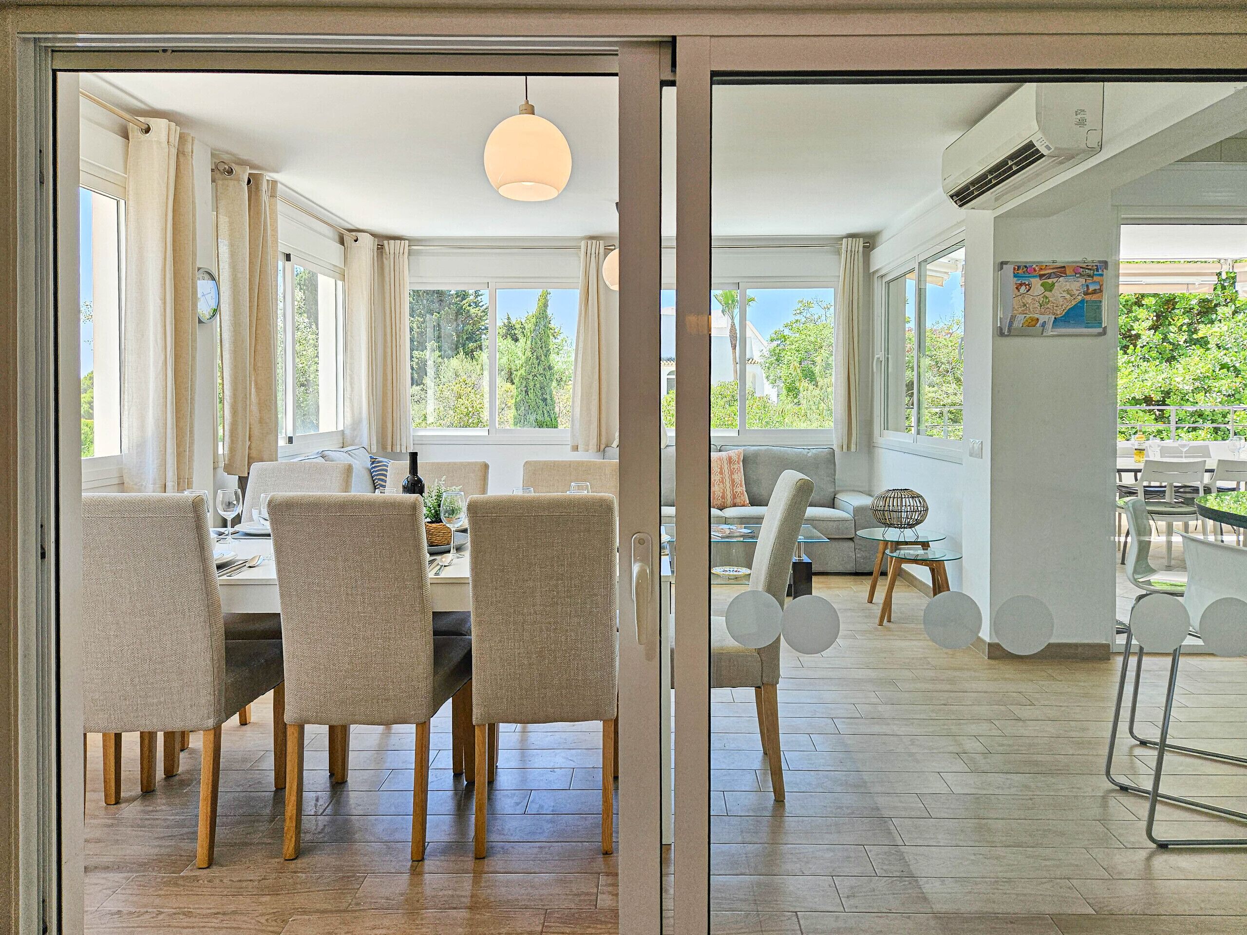 Un espace de repas moderne avec une table dressée pour quatre personnes, un canapé et une vue sur l’extérieur.