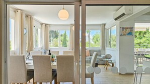 Zona pranzo moderna con tavolo apparecchiato per quattro persone, un divano e vista sull'esterno.