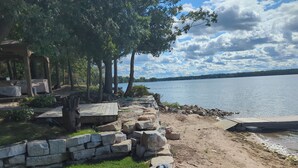 A lakeside property with a stone wall, a wooden deck, and a gazebo.