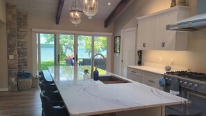A spacious kitchen with a large island, stone wall, and a view of a lake.