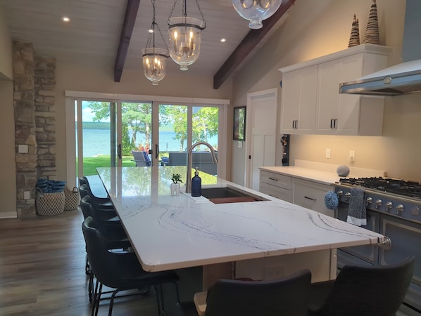 A spacious kitchen with a large island, stone wall, and a view of a lake.