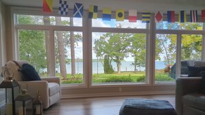 A room with large windows overlooking a lake, furnished with a sofa, ottoman, and decorative items.