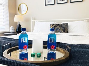 Ein Hotelzimmer mit einem Bett, einem Nachttisch mit Lampe und einer Schale mit zwei Fiji-Wasserflaschen.