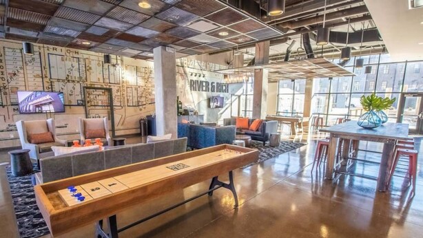 A spacious lobby with a shuffleboard table, comfortable seating, and a large TV screen. - City View 2BR Free Parking Pet-friendly (Columbus)