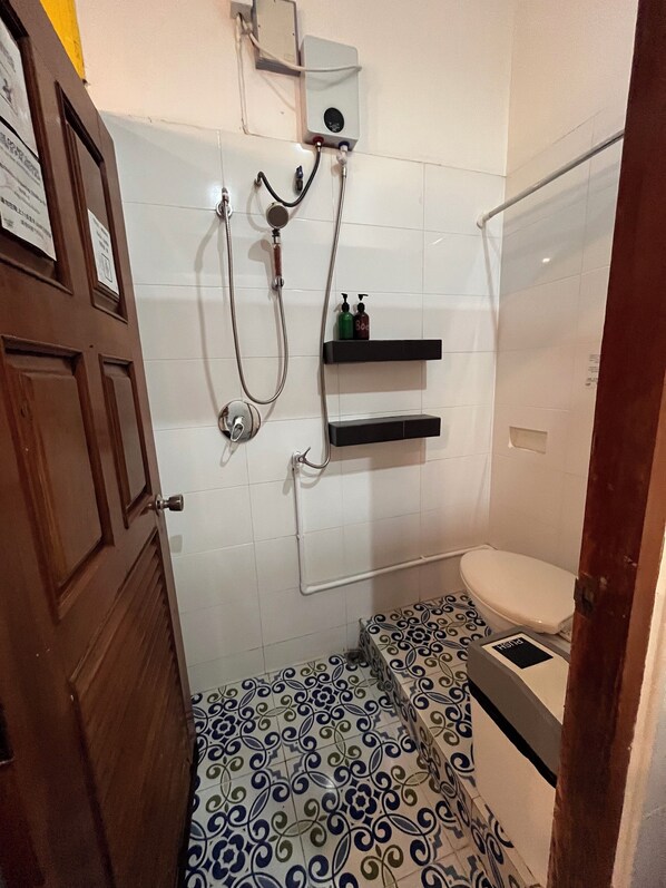 Un baño con ducha, inodoro y suelo con baldosas estampadas.