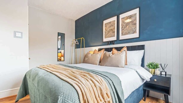 Un dormitorio con cama, mesita de noche y decoración en la pared.