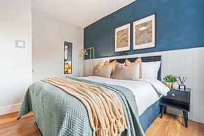 A bedroom with a bed, bedside table, and wall art.